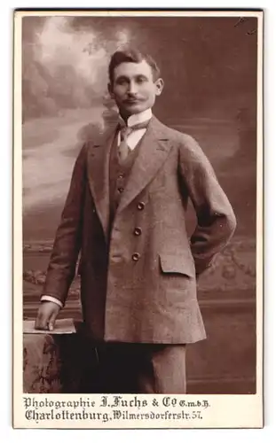 Fotografie J. Fuchs & Co., Charlottenburg, Wilmersdorferstrasse 57, Portrait Herr im grauen Anzug mit Zwirbelbart