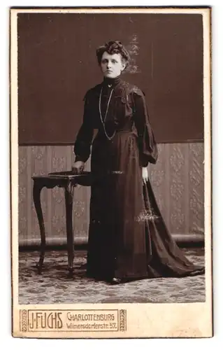 Fotografie J. Fuchs, Charlottenburg, Wilmersdorferstrasse 57, Dame im schwarzen Kleid mit Halskette, Hochsteckfrisur