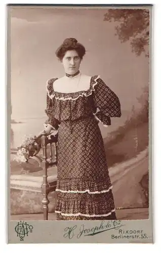Fotografie H. Joseph & Co., Rixdorf, Berlinerstrasse 55, Portrait Frau im Pünktchenkleid mit Hochsteckfrisur