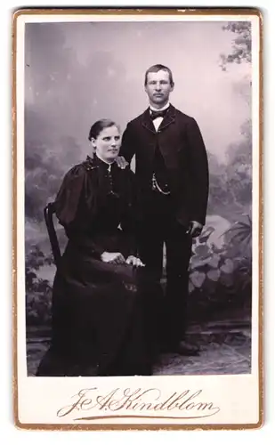 Fotografie F. A. Kindblom, Gislaved, Portrait Mann und Frau im Anzug und Biedermeierkleid vor einer Studiokulisse