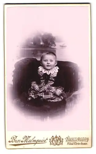 Fotografie Bror Malmquist, Skillingaryd, Portrait Kind im karierten Kleid mit Spitzenkragen im Sessel sitzend