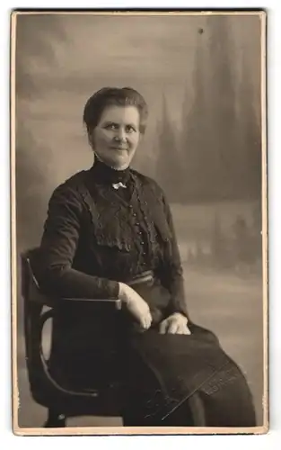 Fotografie Fotograf und Ort unbekannt, Portrait Dame im Biedermeierkleid mit Brosche vor einer Studiokulisse