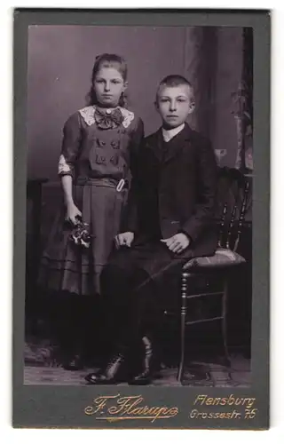 Fotografie F. Flarup, Flensburg, Grossestrasse 75, Portrait Bruder und Schwester im Anzug und Kleid mit Schleife