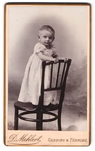 Fotografie D. Mehlert, Garding, Portrait kleines Mädchen im weissen Kleid steht auf einem Stuhl