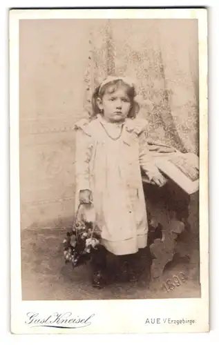 Fotografie Gust. Kneisel, Aue i. Erzg., Portrait kleines Mädchen im weissen Kleid mit Haarschleife schaut weinerlich