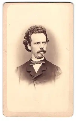 Fotografie Gustaf Reiger, Augsburg, Spengelgasse 94, Portrait Herr im Anzug mit Fliege und Locken, Oberlippenbart