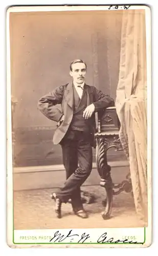 Fotografie Isaac Preston, Leeds, North Street 105, Portrait kleiner Mann im Anzug an einem Sekretär gelehnt
