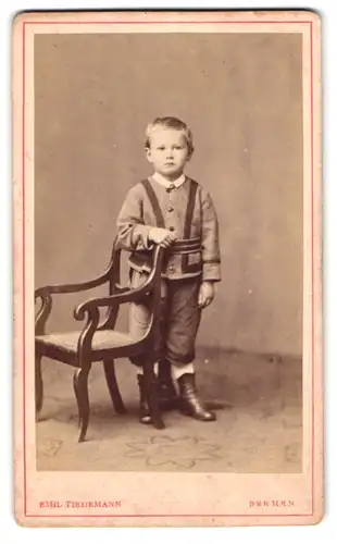 Fotografie Emil Tiedemann, Bremen, Richtweg 12, Portrait niedlicher blonder Knabe im Anzug neben einem Stuhl