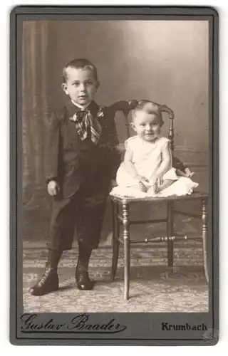 Fotografie Gustav Baader, Krumbach, Knabe im Anzug und Kleinkind auf einem Stuhl