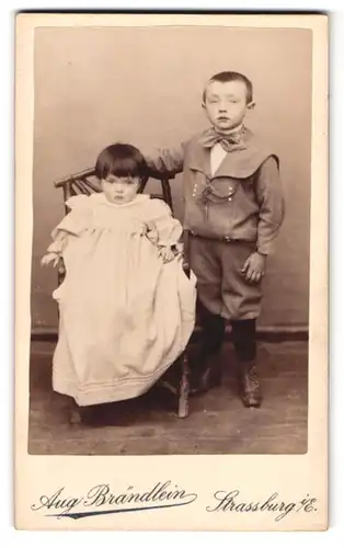 Fotografie Aug. Brändlein, Strassburg i. E., Ziegelauweg 9, Kleinkind in weissem Kleid mit ihrem grossen Bruder