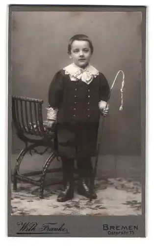 Fotografie Wilh. Franke, Bremen, Osterstr. 75, Portrait junger Knabe im Anzug mit Reitgerte in der Hand