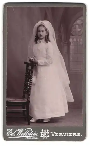 Fotografie Ed. Wettstein, Verviers, Portrait Mädchen im weissen Kleid mit Schleier zur Kommunion, Kirchenkulisse