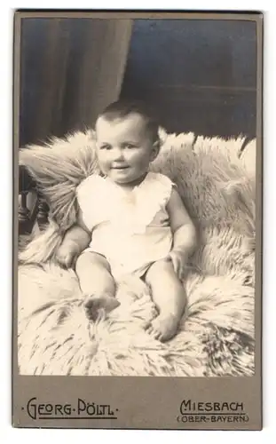 Fotografie Gebr. Pöltl, Miesbach, Rathausstrasse 67, Kleines Kind im weissen Hemd auf einem Fell