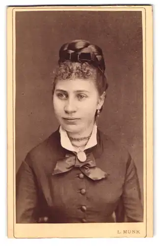 Fotografie L. Munk, Troppau, Sperrgasse 35, Junge Dame im Kleid mit Halskette, Ohrringen und Dutt