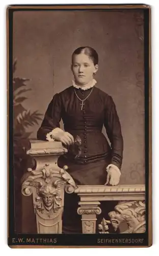 Fotografie E. W. Matthias, Seifhennersdorf, Portrait Elegante Frau mit Kreuzkette in geknöpftem Kleid