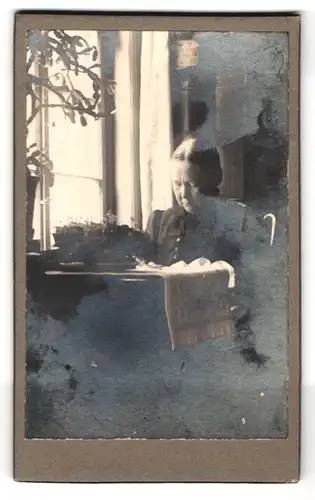 Fotografie unbekannter Fotograf und Ort, Portrait Ältere Frau im Kleid sitzt am Tisch