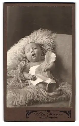 Fotografie Wilhelm Mayer, Esslingen, Kronenstrasse 14, fröhliches Kleinkind auf Schafsfell
