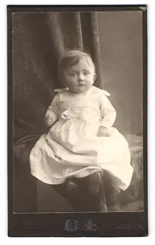 Fotografie J. Fuchs, Berlin, Neue Friedrichstrasse 108, Portrait Kleinkind im weissen Kleid mit blonden Haaren