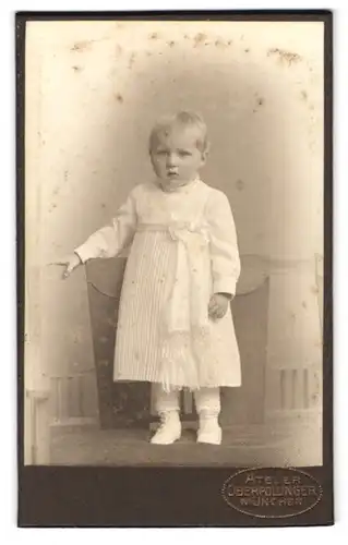 Fotografie Oberpollinger, München, Portrait kleines blondes Mädchen im weissen Kleid mit Schleife