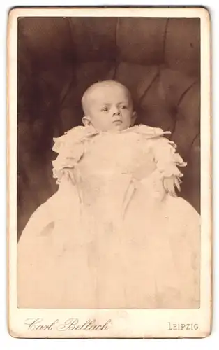 Fotografie Carl Bellach, Leipzig, Gellert-Strasse 12, Portrait Kleinkind im weissen Kleid auf einem Sofa liegend