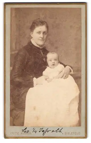Fotografie Fritz Küken, Bielefeld, Victoriastrasse, Portrait Mutter in dunklen Kleid zeigt stolz ihren Sohn Leo