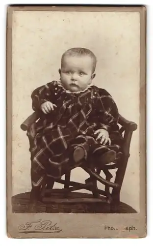 Fotografie F. Petz, Duderstadt, Portrait kleines Kind im karierten Kleid sitzt auf einem Kinderstuhl