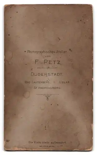 Fotografie F. Petz, Duderstadt, Portrait kleines Kind im karierten Kleid sitzt auf einem Kinderstuhl