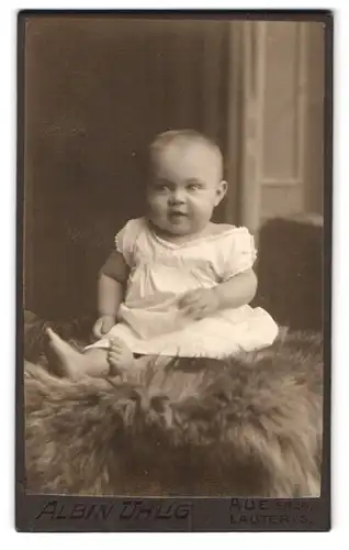 Fotografie Albin Uhlig, Aue i. S., Bahnhofstrasse 11, lächelndes Kleinkind in weissen Kleidchen