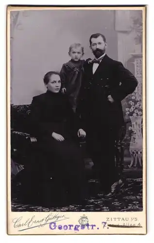Fotografie Carl Ernst Güttges, Zittau i. S., Circus-Allee 4, gut gekleidetes Ehepaar mit ihrem Kind
