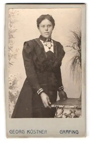 Fotografie Georg Köstner, Grafing, Portrait junge Dame im schwarzen Kleid vor einer Studiokulisse