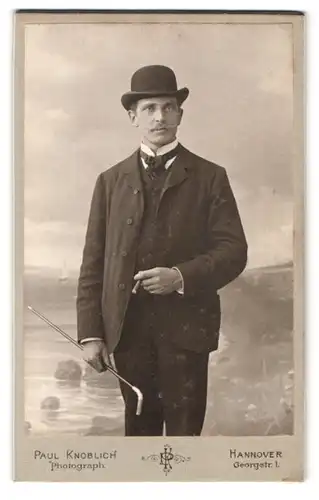 Fotografie Paul Knoblich, Hannover, Georgstr. 1, Portrait Herr im Anzug mit Melone und Flanierstock vor Studiokulisse