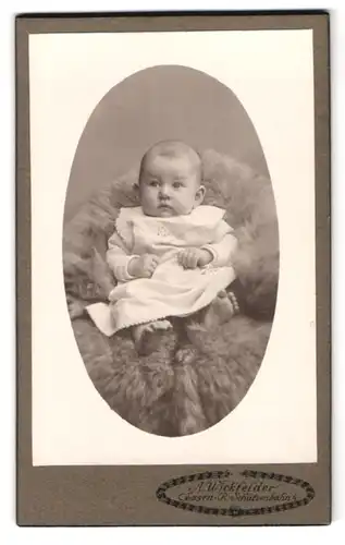 Fotografie A. Wickfelder, Essen a. d. Ruhr, Schützenbahn 4, Portrait Kleinkind im weissen Kleid auf einem Fell liegend
