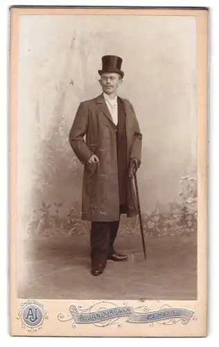 Fotografie A. Jandorf, Berlin, Spittelmarkt 16-17, eleganter Herr mit Zylinder & Spazierstock vor Studiokulisse