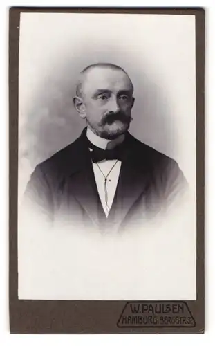 Fotografie W. Paulsen, Hamburg, Bergstr. 3, Portrait Herr mit Schnauzbart und Glatze im Anzug