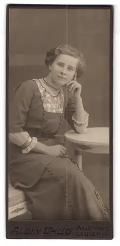 Fotografie Albin Uhlig, Aue i. Erzg., Bahnhofstr. 11, Portrait junge Frau im grauen Kleid stützt sich auf Ellenbogen
