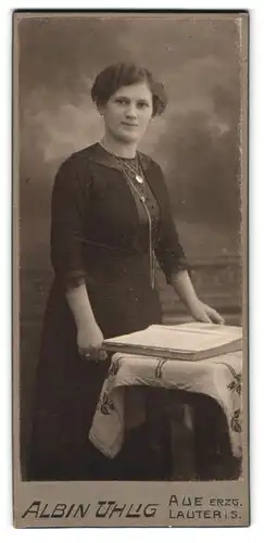 Fotografie Albin Uhlig, Aue i. Erzg., Bahnhofstr. 11, Portrait Dame im schwarzen Kleid mit Fotoalbum auf dem Tisch