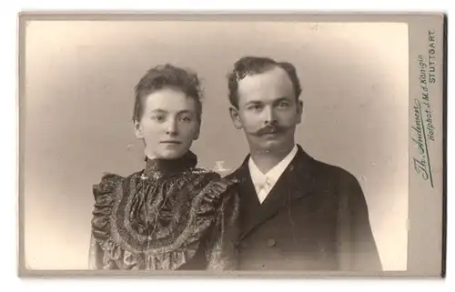 Fotografie Th. Andersen, Stuttgart, Charlottenstr. 8, Portrait Frau und Mann im Kleid mit Brosche und Anzug, Zwirbelbart