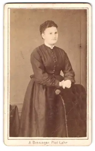 Fotografie A. Binninger, Lahr, Portrait Dame im Biedermeierkleid lehnt an einem Sessel