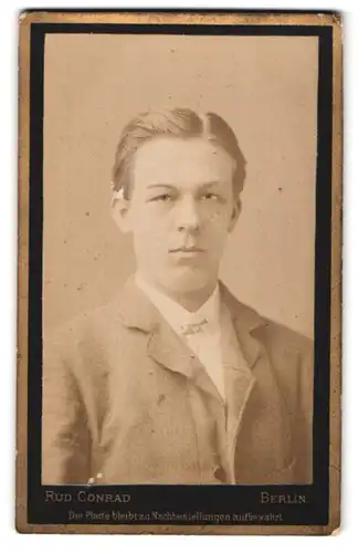 Fotografie Rud. Conrad, Berlin, Alexanderstr. 44, Portrait junger Mann im grauen Anzug mit Mittelscheitel