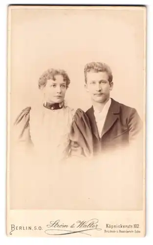 Fotografie Strom & Walter, Berlin, Köpenickerstr. 102, Portrait Mann und Frau im Anzug und Kleid mit Locken