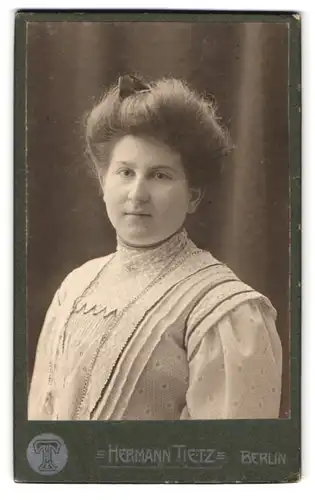 Fotografie Hermann Tietz, Berlin, Leipziger-Str. 46-50, Portrait rundliche Frau im weissen Kleid mit Haarschleife