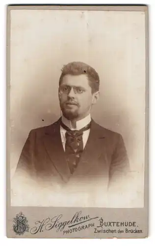 Fotografie H. Siggelkow, Buxtehude, Zwischen den Brücken, Portrait Herr im Anzug mit breiter Krawatte, Zwicker Brille