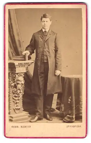 Fotografie Gebr. Martin, Augsburg, Bahnhofstr., Portrait Herr im Anzug mit Mantel posiert im Atelier