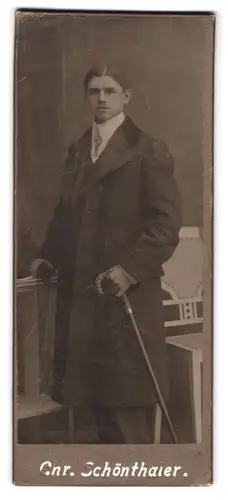 Fotografie Chr. Schönthaler, Karlsruhe, Portrait junger Mann im Anzug mit Mantel und Flanierstock