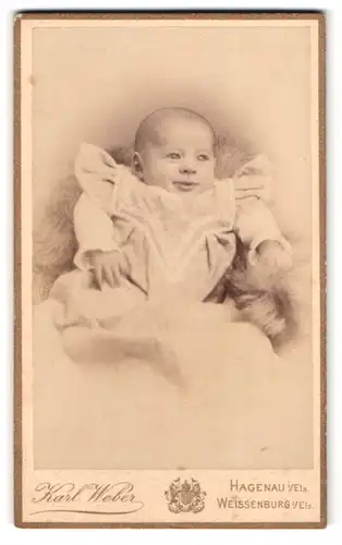 Fotografie Karl Weber, Hagenau / Elsass, fröhliches Baby auf Decke liegend