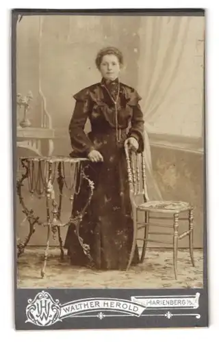 Fotografie Walter Herold, Marienberg / Sachsen, Junge Frau im dunklen Kleid neben einem Beistelltisch