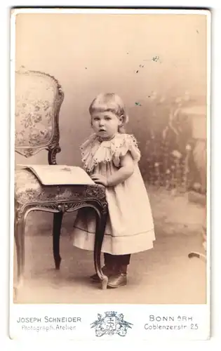 Fotografie Joseph Schneider, Bonn a. Rh., Coblenzerstrasse 25, Portrait kleines Mädchen im Kleid mit einem Buch