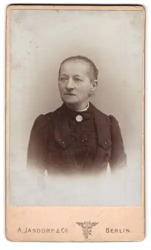 Fotografie A. Jandorf & Co., Berlin, Spittelmarkt 16-17, Portrait betagte Dame mit Kragenbrosche im schwarzen Kleid