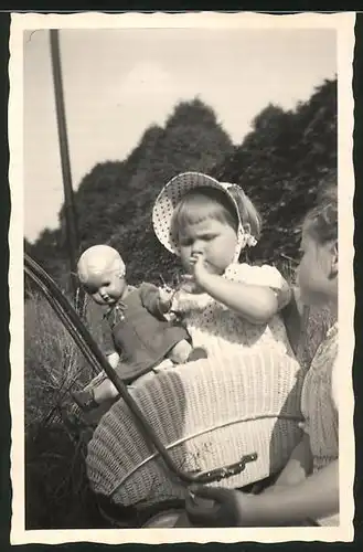 Fotografie Mädchen im Kinderwagen spielt mit ihrer Puppe