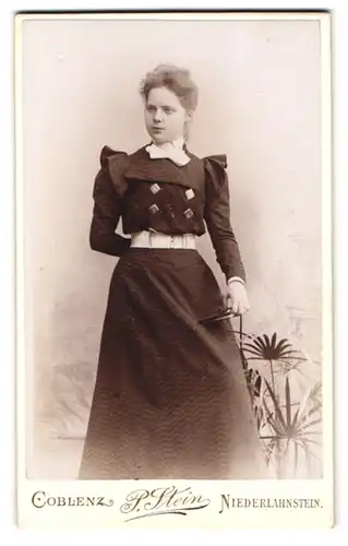Fotografie P. Stein, Koblenz, Löhrstr. 77, Dame im eleganten Kleid mit Buch und weissem Gürtel